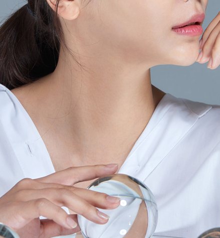 흰 셔츠 여성 모델의 턱·목선과 유리구를 든 손